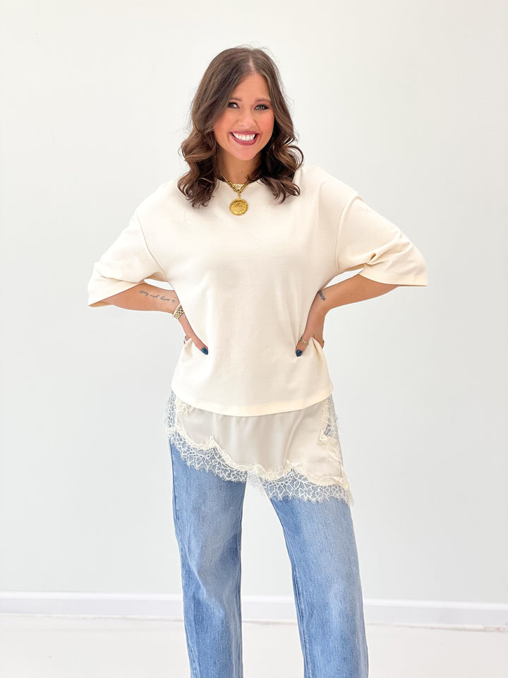 Ivory short-sleeve top with asymmetric lace-trim hem and scalloped edges