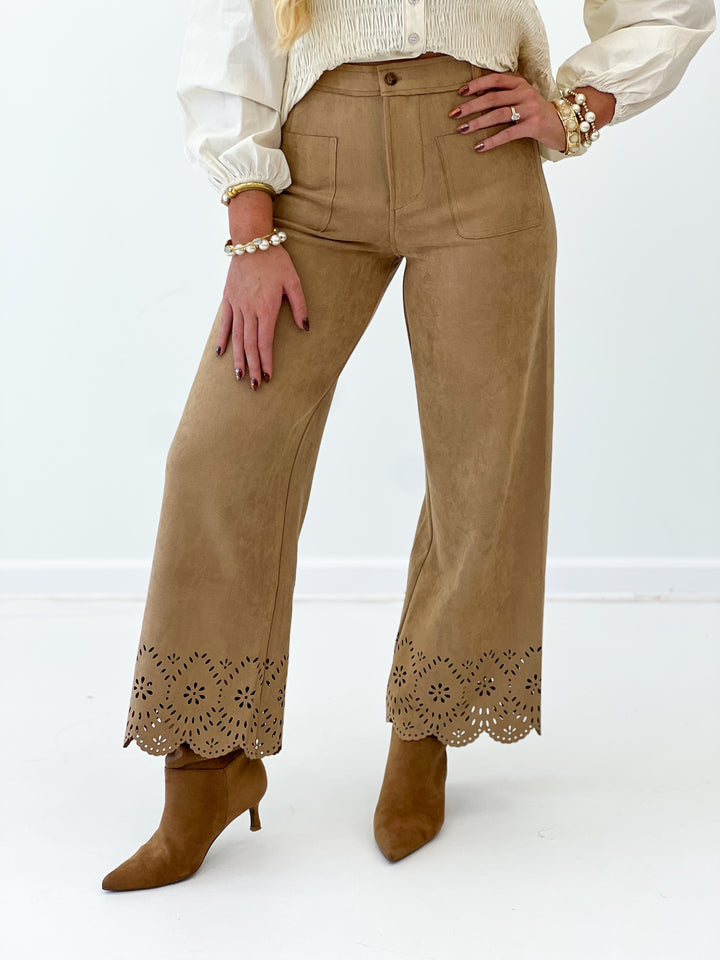 Camel suede wide-leg pants close-up: laser-cut hem border and front pocket seams