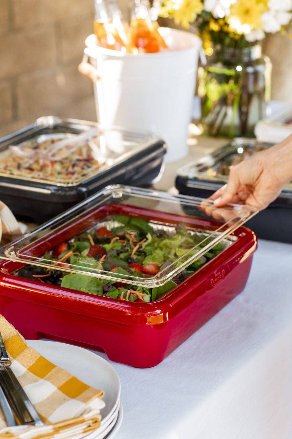 Red foil pan carrier with clear foil pan and lid, holding prepared meal