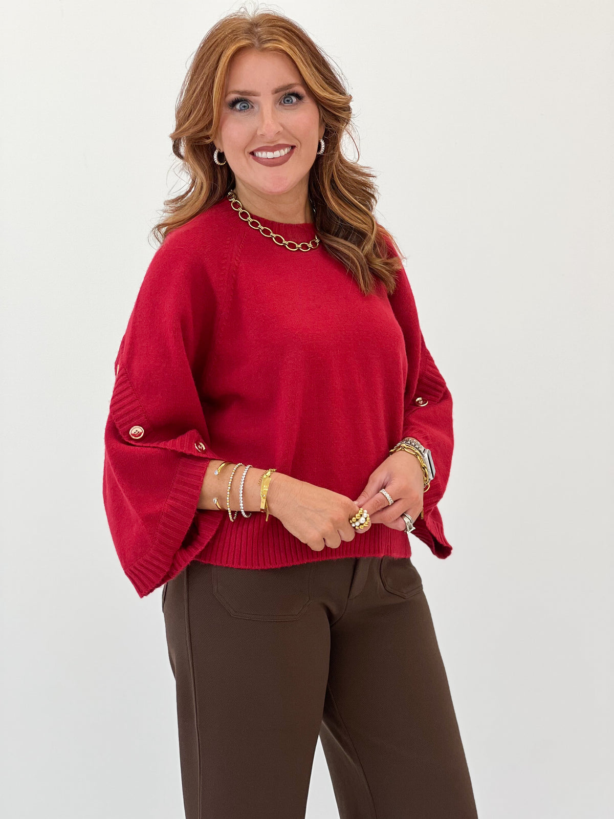 Women's red knit sweater with poncho sleeves and button-detail cuffs