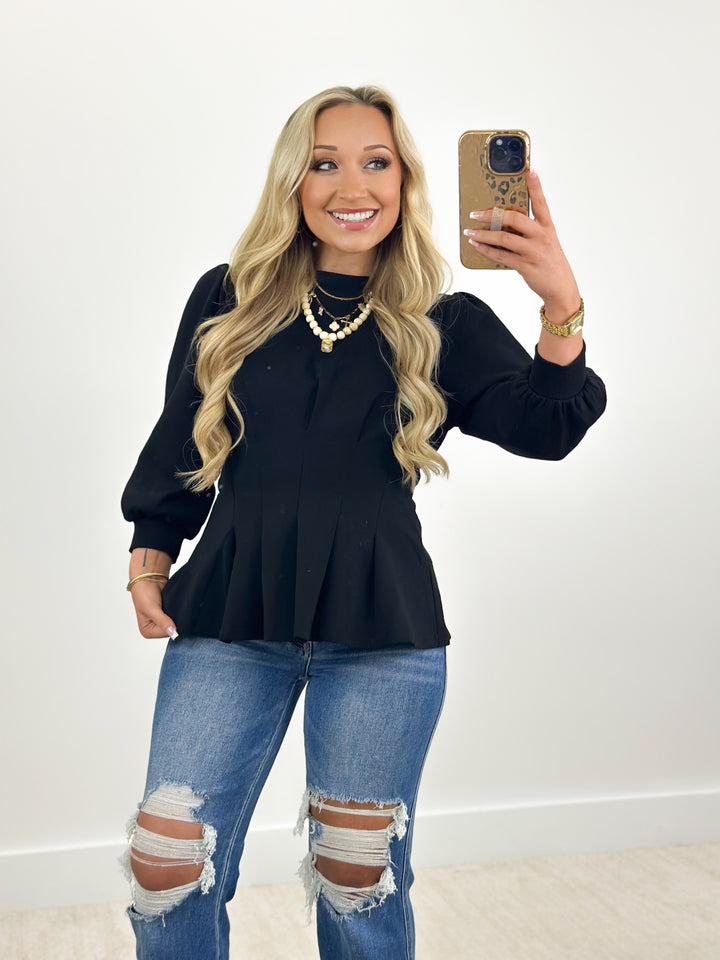 Black pleated flare top with ribbed knit collar and long sleeves