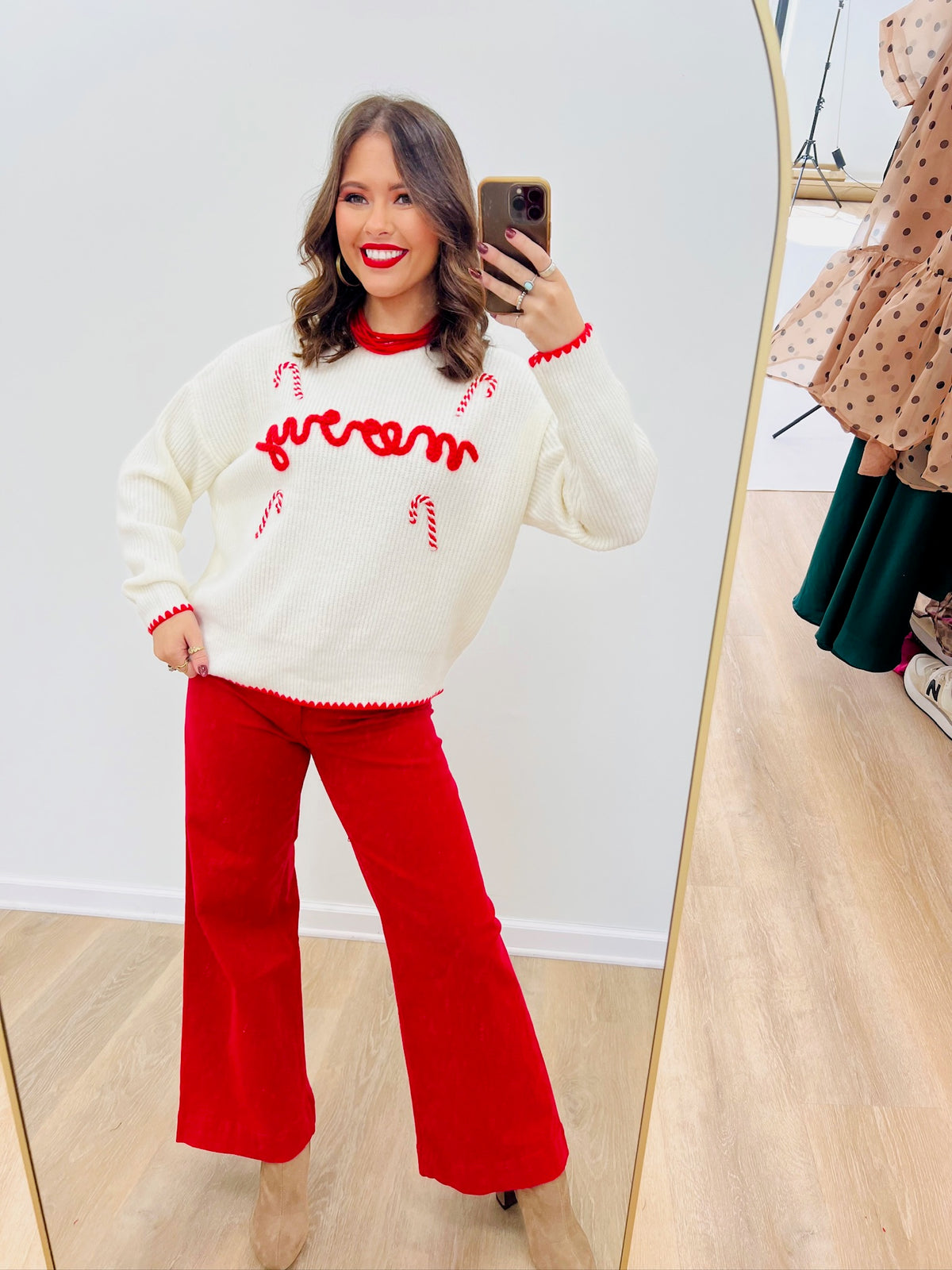 Off-white knit sweater with red “merry” embroidery and candy-cane trim cuffs
