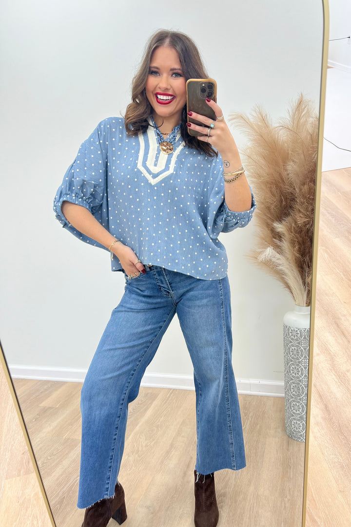 Light blue polka dot V-neck top with contrast trim and loose sleeves