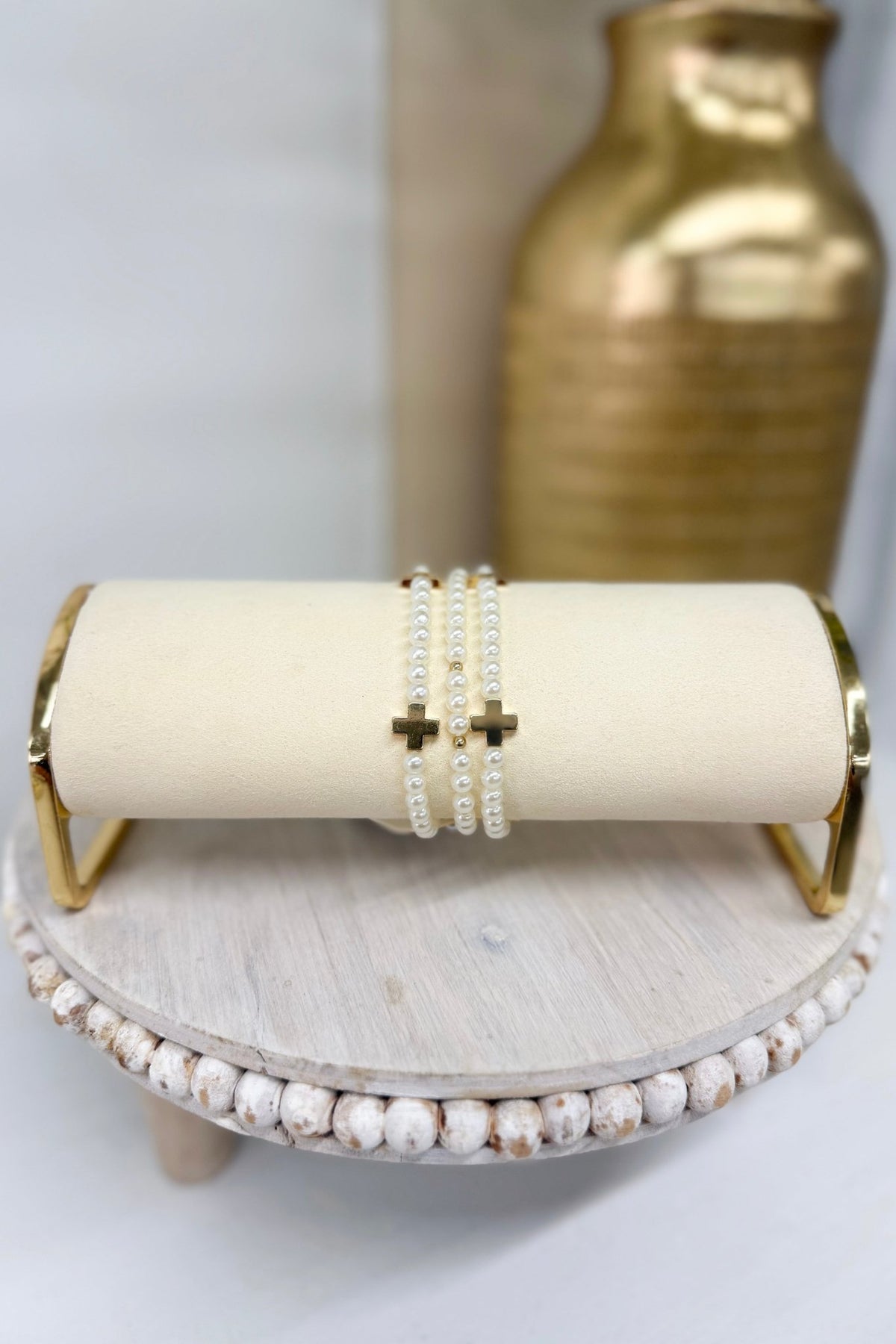 Three-row cream bracelet with a gold cross charm