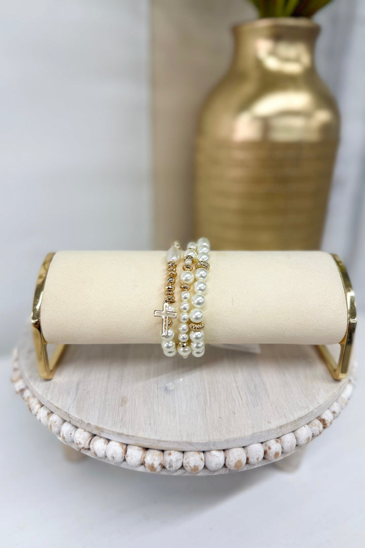 Three-row cream pearl bracelet with a gold cross charm