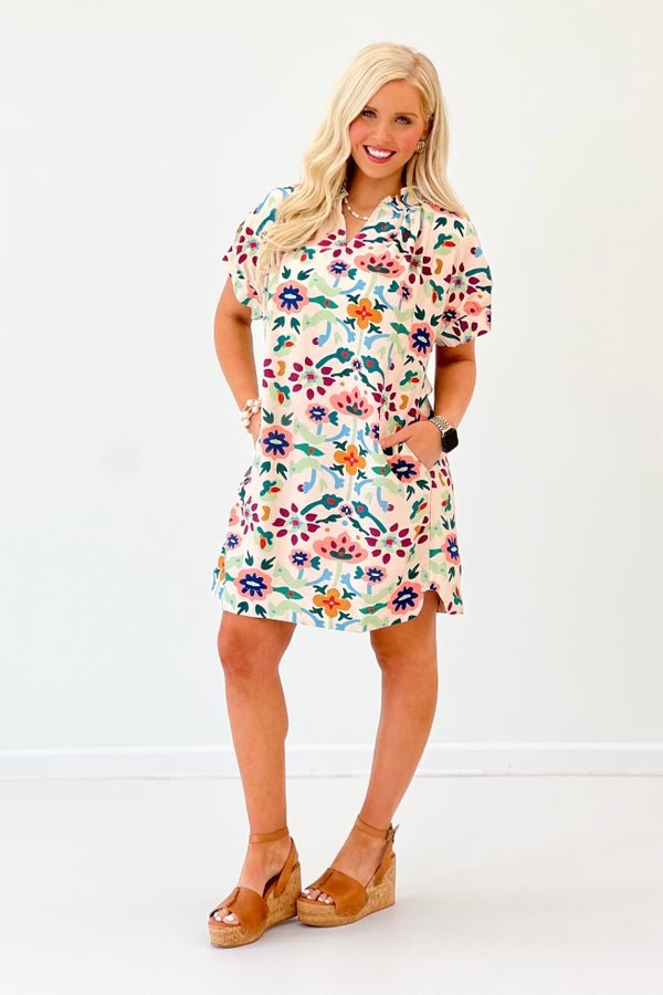 Ecru pleated dress with a V-neckline and embroidered accents