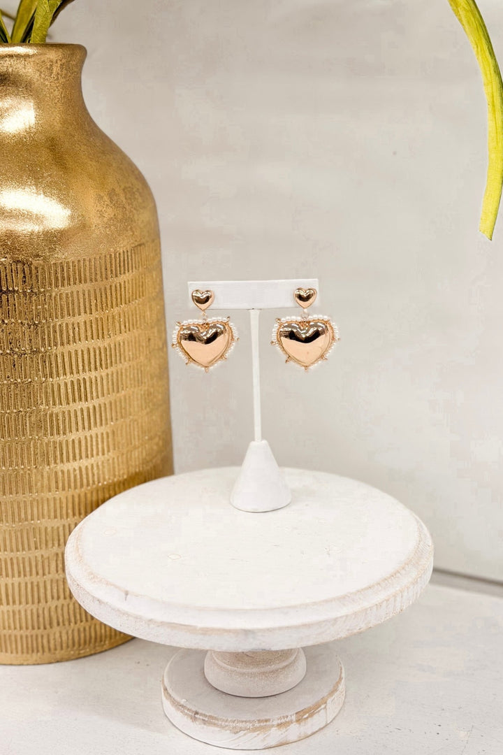 Gold earrings with two hearts and a cream pearl drop