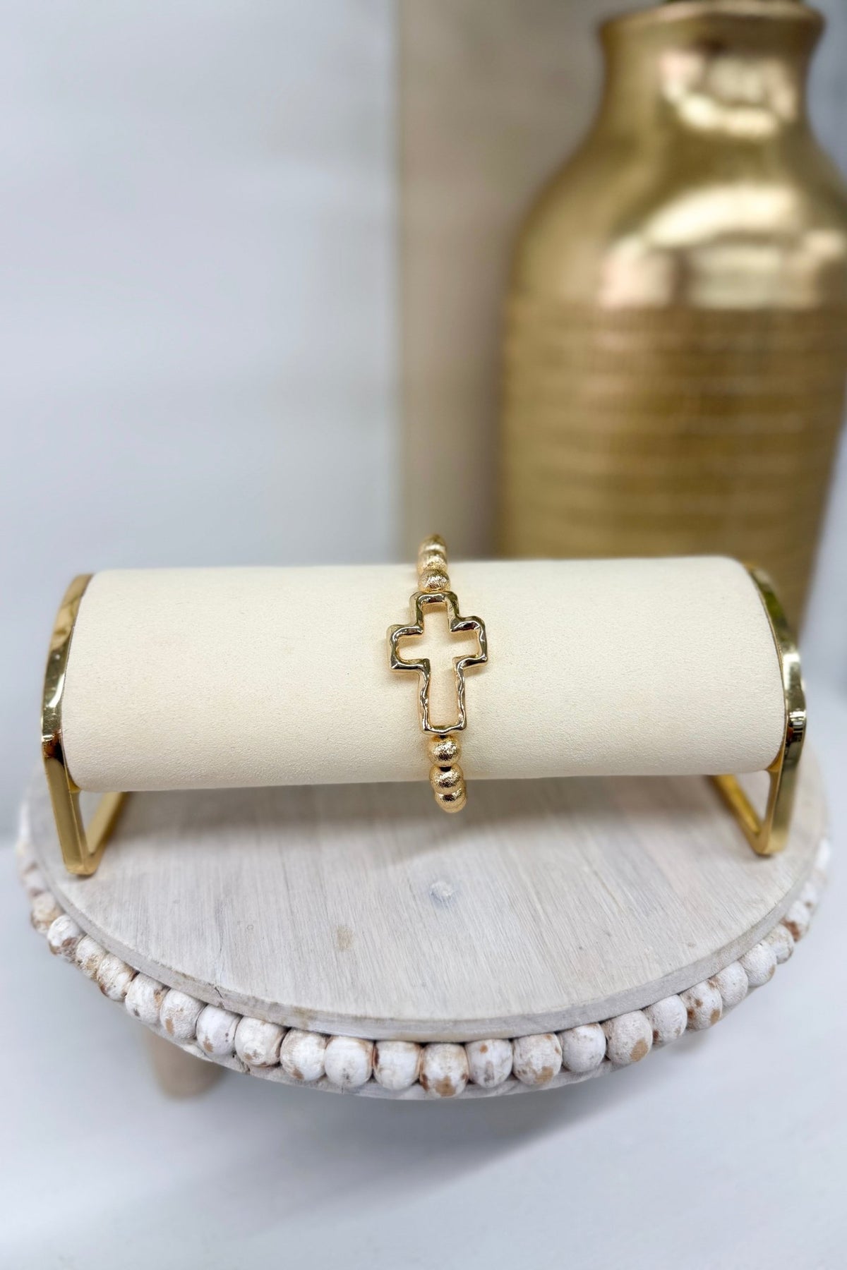 Gold textured metal bracelet with a cross accent