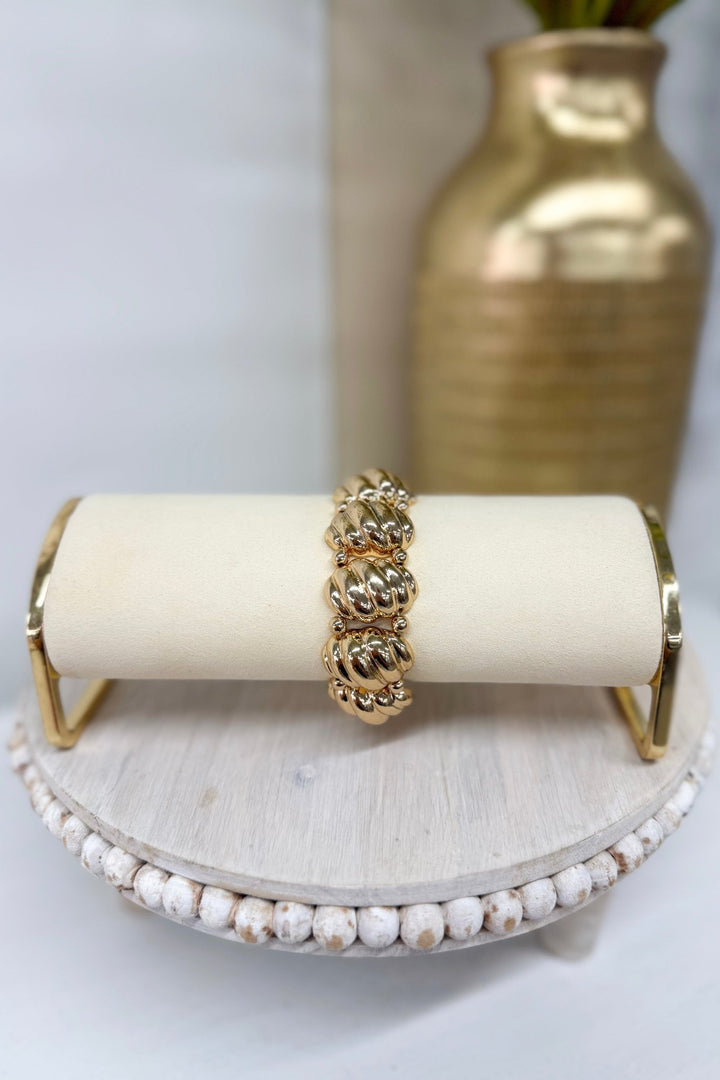 Gold oval metal bracelet with a ribbed texture