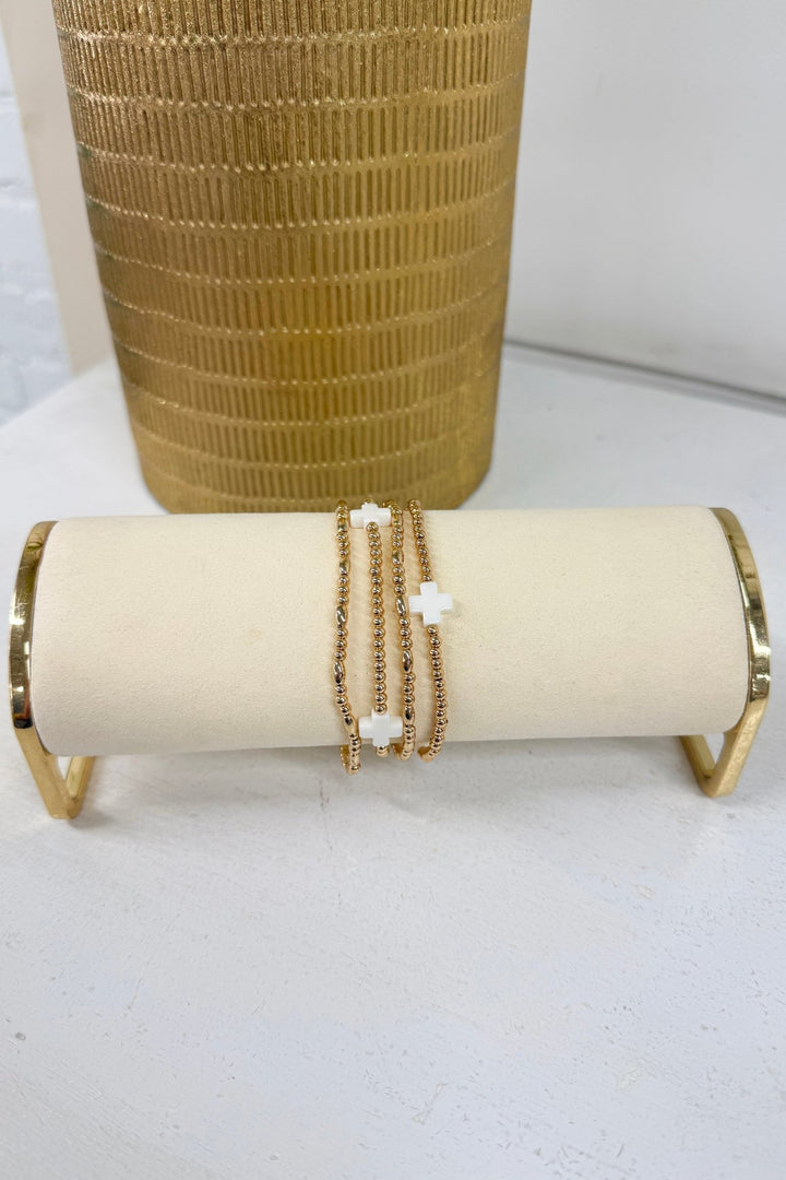 White four-row beaded bracelet with a gold cross