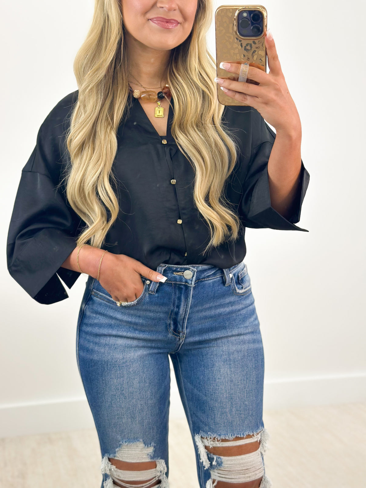 Close-up black V-neck button-down shirt with metal buttons and necklace collar