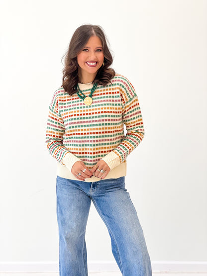 Multi-color striped sweater with gold button pendant at crew neckline, long sleeves