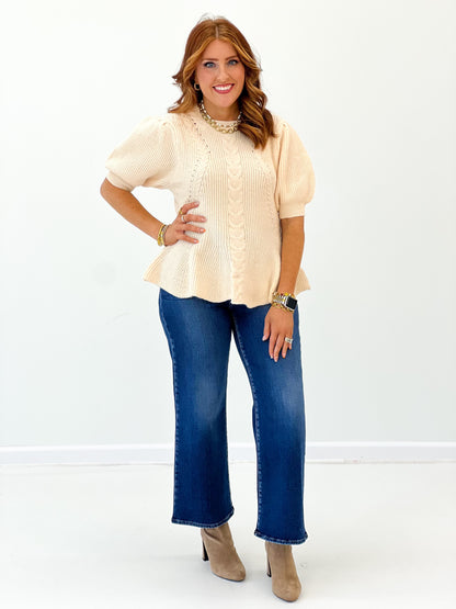 Ivory knit sweater top with round neck, short sleeves, peplum-style flare hem