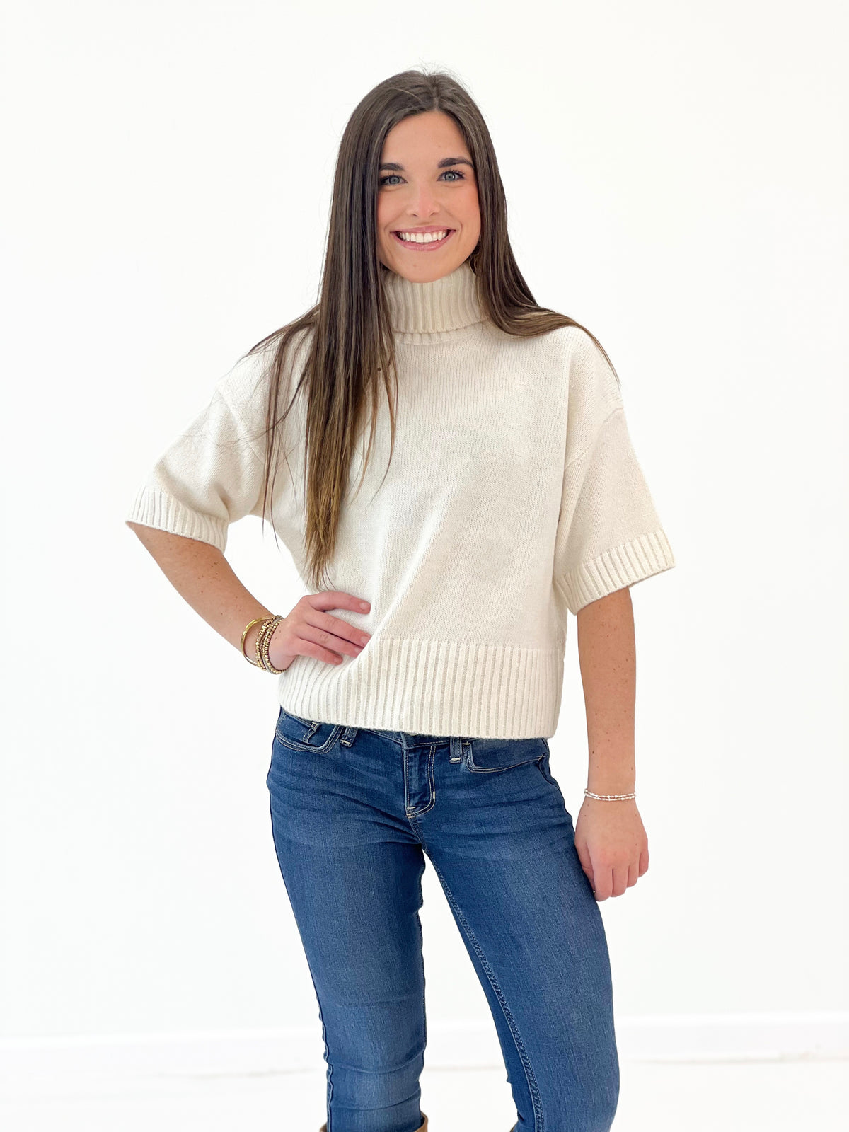 Off-white knit turtleneck sweater with short sleeves and ribbed cuffs
