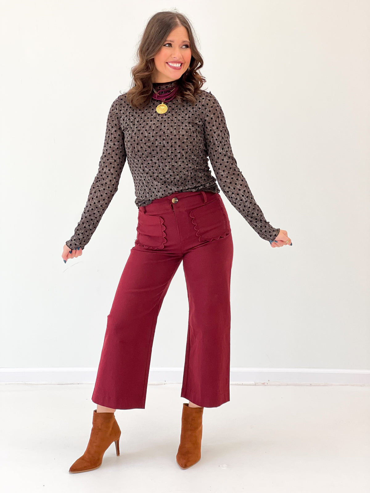 Black polka dot mock-neck long-sleeve top, allover small dots shown in full body view.