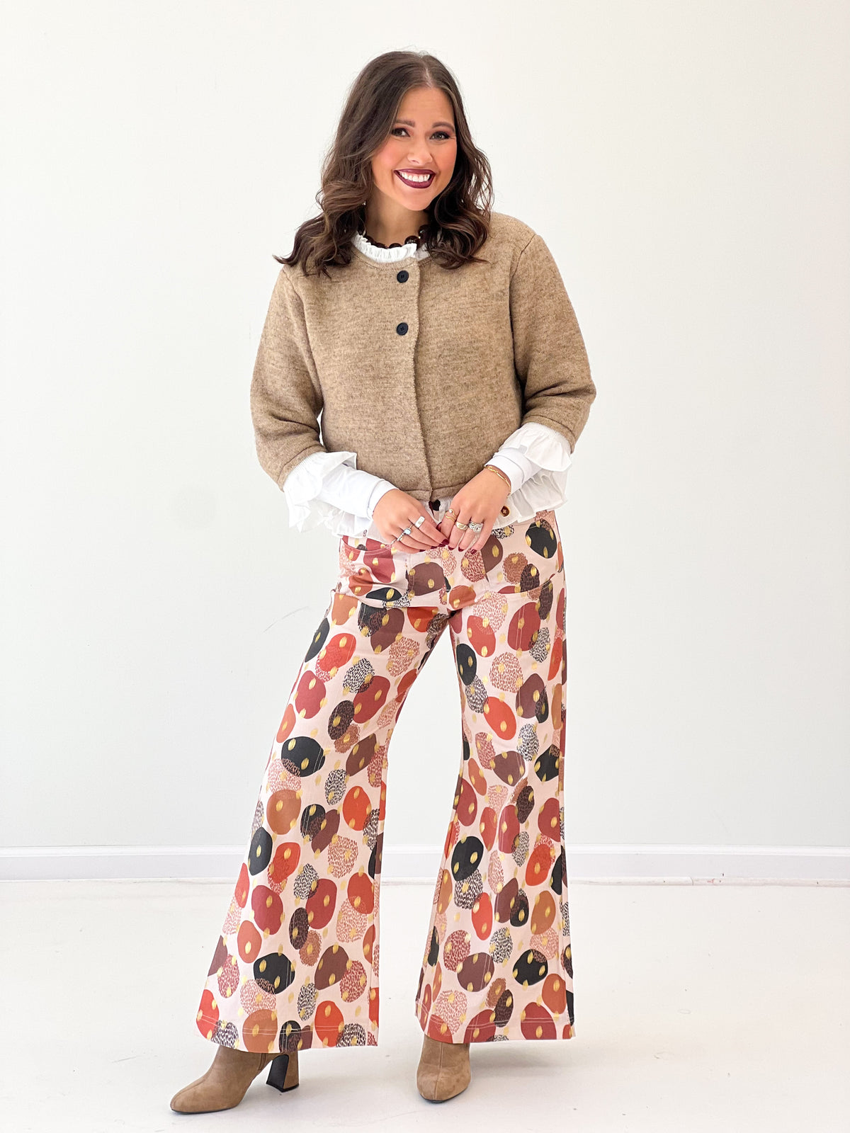 Mocha knitted cardigan top with rounded neckline, black buttons, and white ruffle hem