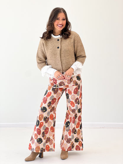 Mocha knitted cardigan top with rounded neckline, black buttons, and white ruffle hem
