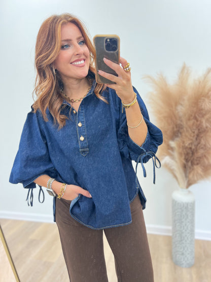 Dark denim puff-sleeve top detail: button placket and drawstring cuffs