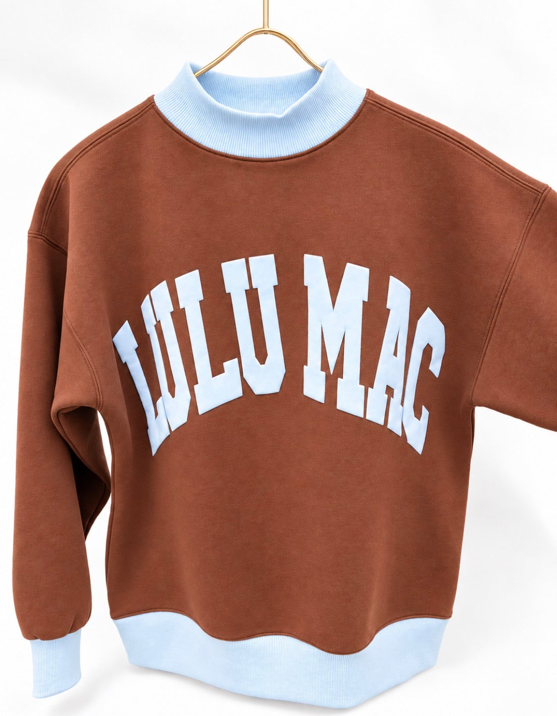 Brown puff mock neck sweatshirt with light blue ribbed collar, hem, and white logo print