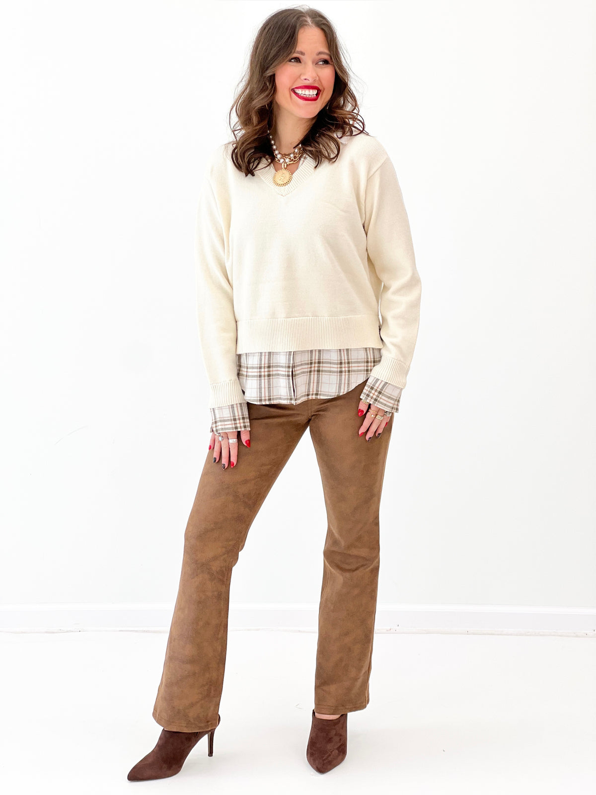 Cream long-sleeve sweater layered with plaid shirt at waist and collar