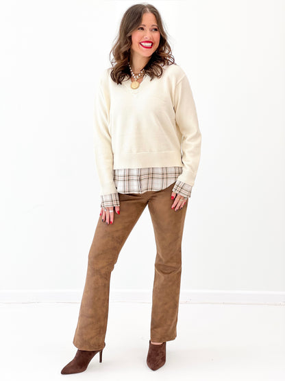 Cream long-sleeve sweater layered with plaid shirt at waist and collar