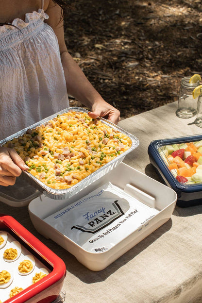 White insulated carrier with foil pan and serving tray on a table