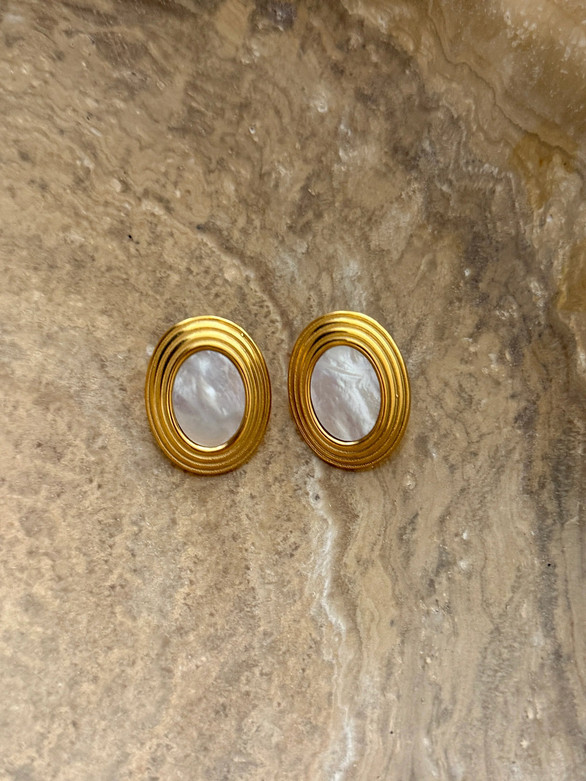 Gold-tone round hoop earrings with ribbed edges and white mother-of-pearl insets