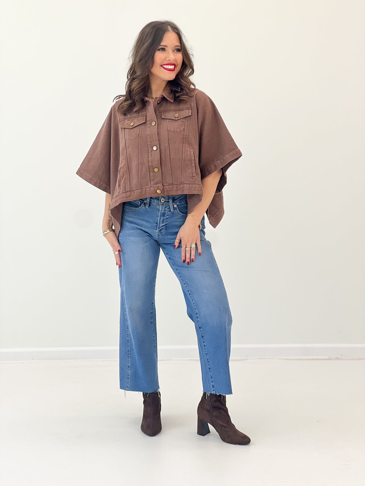 Brown cropped denim jacket with short sleeves, snap front, and chest flap pockets