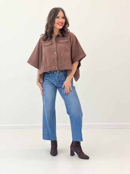 Brown cropped denim jacket with short sleeves, snap front, and chest flap pockets
