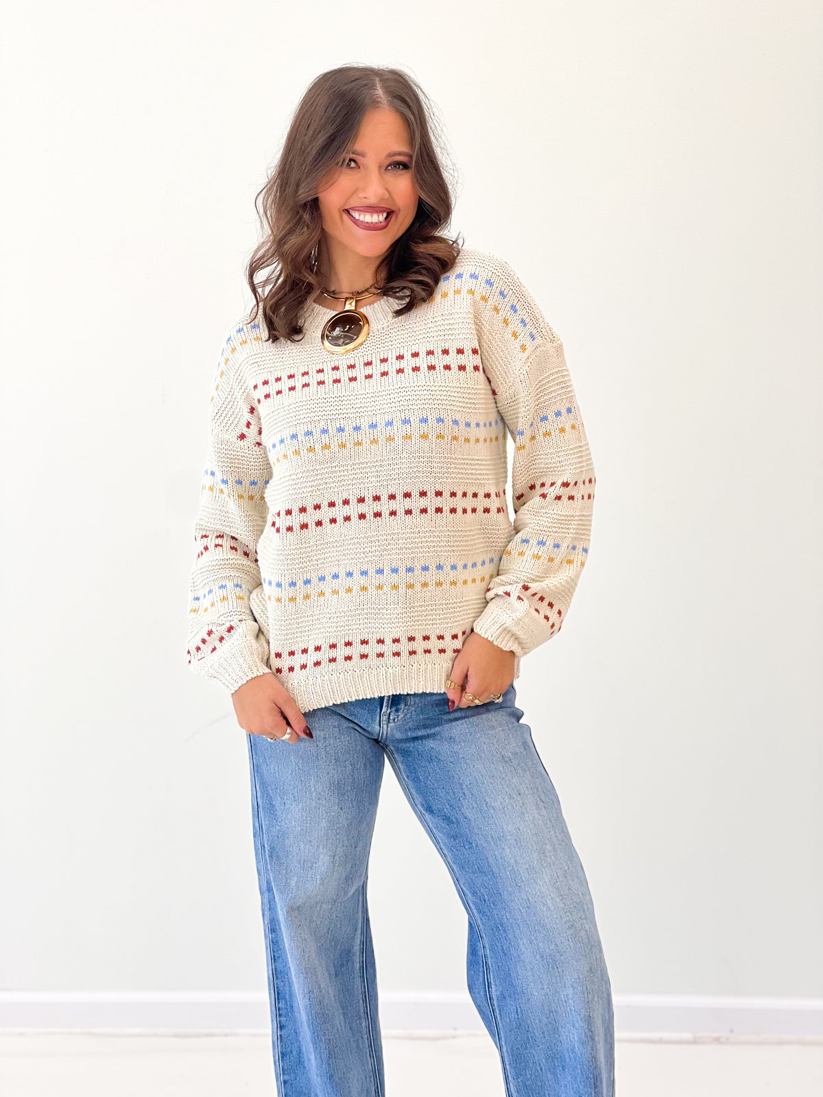 Cream knit long-sleeve sweater with multicolor striped rows and crew neckline