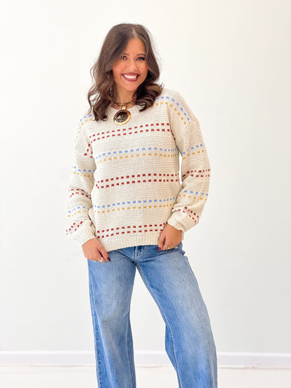 Cream knit long-sleeve sweater with multicolor striped rows and crew neckline