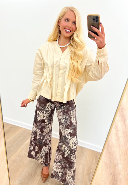 Cream V-neck pleated-waist blouse with long sleeves and gathered front yoke.