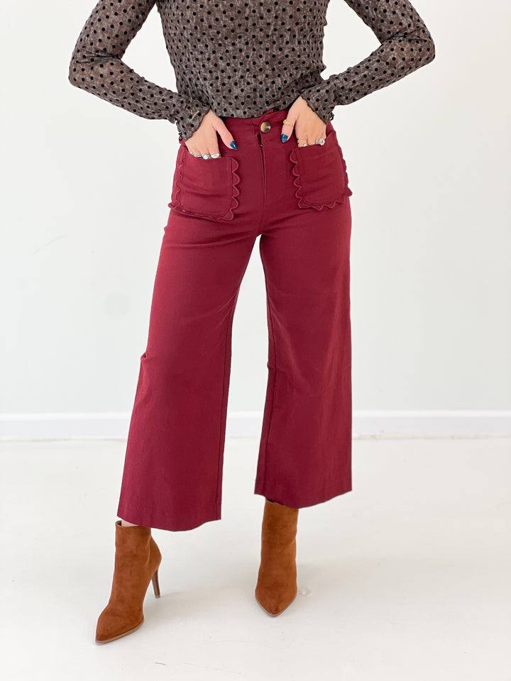 Burgundy cropped wide-leg pants with scalloped ruffle trim down the front