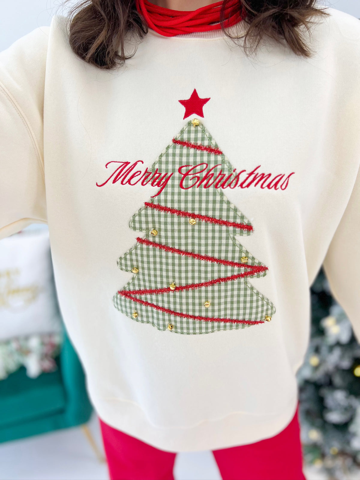 Cream sweatshirt with Christmas tree graphic and red cursive “Merry Christmas” lettering