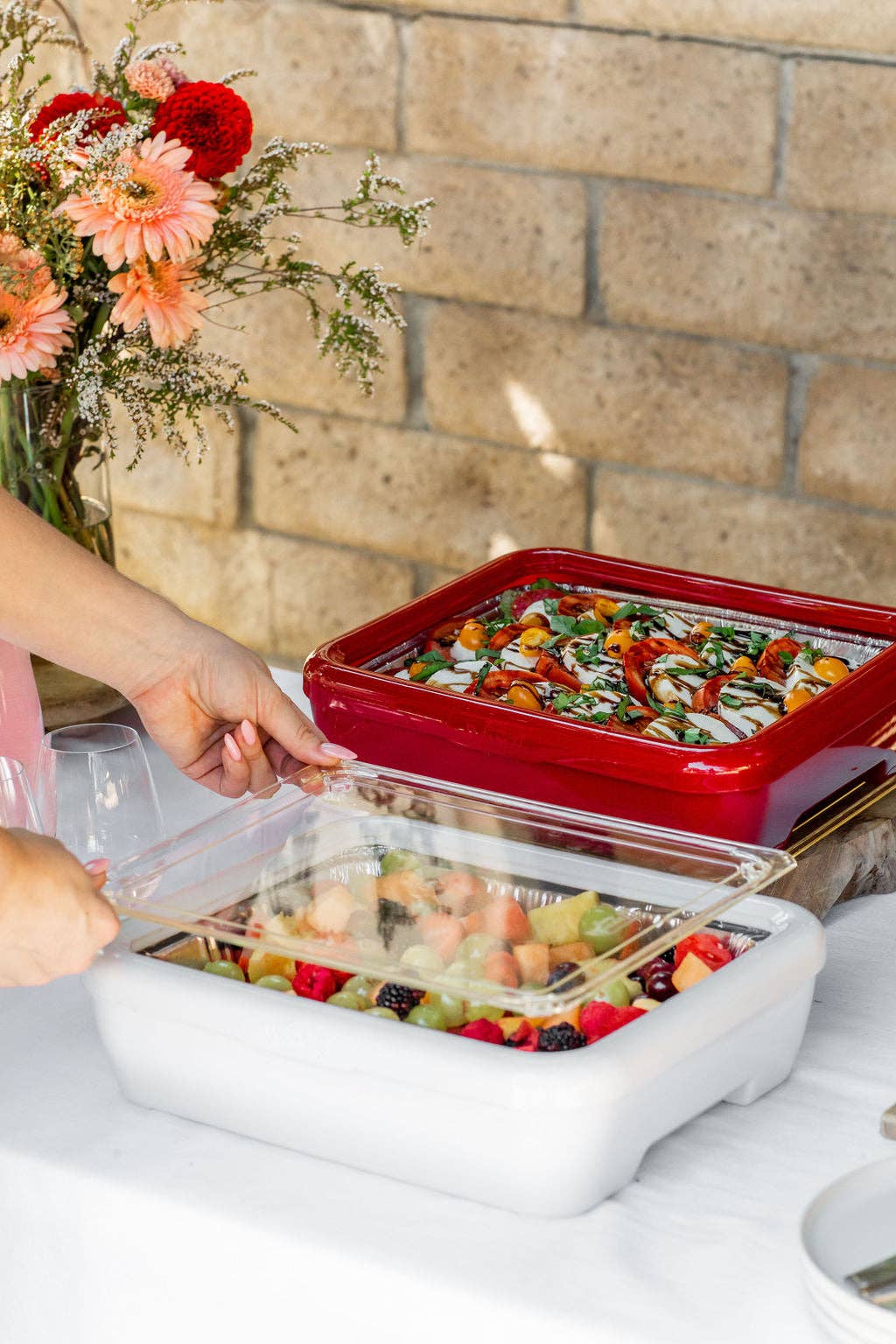 White insulated carrier holding foil pan with vegetables, covered by clear lid