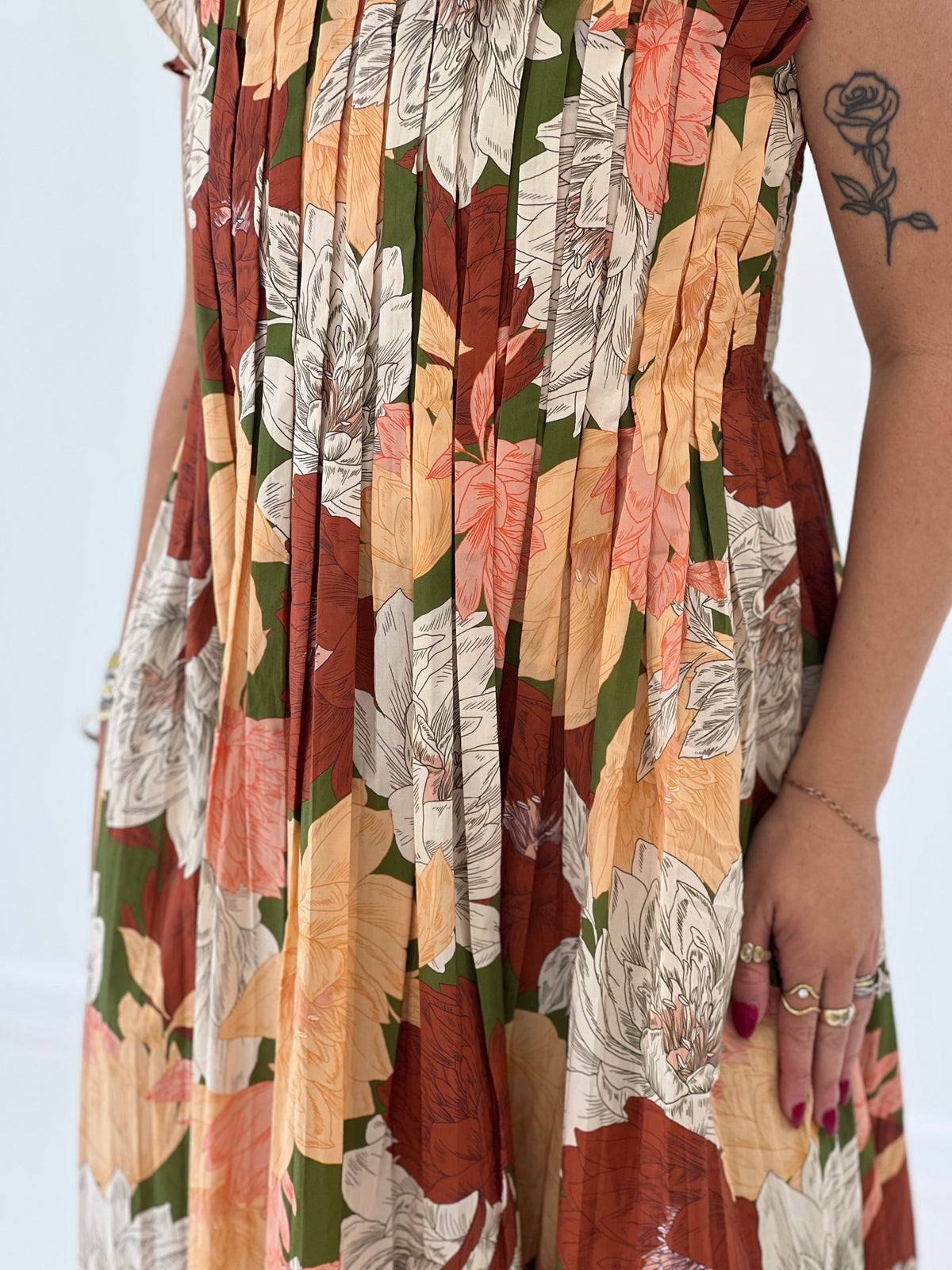 Floral midi dress fabric close-up showing pleated texture and multicolor leaf-and-flower print