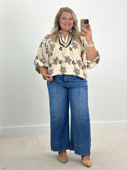 Ecru floral print collared V-neck blouse with black outline flowers and cuffed sleeves