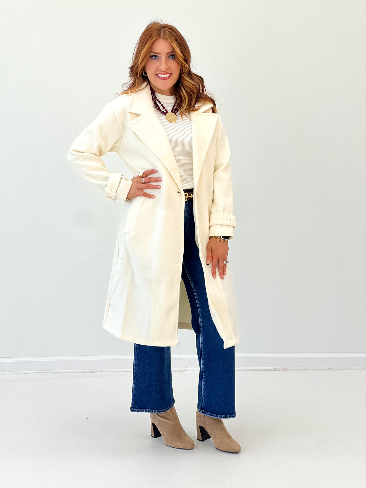 Cream longline coat with notch collar, button front, and cuffed long sleeves