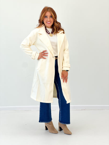 Cream longline coat with notch collar, button front, and cuffed long sleeves