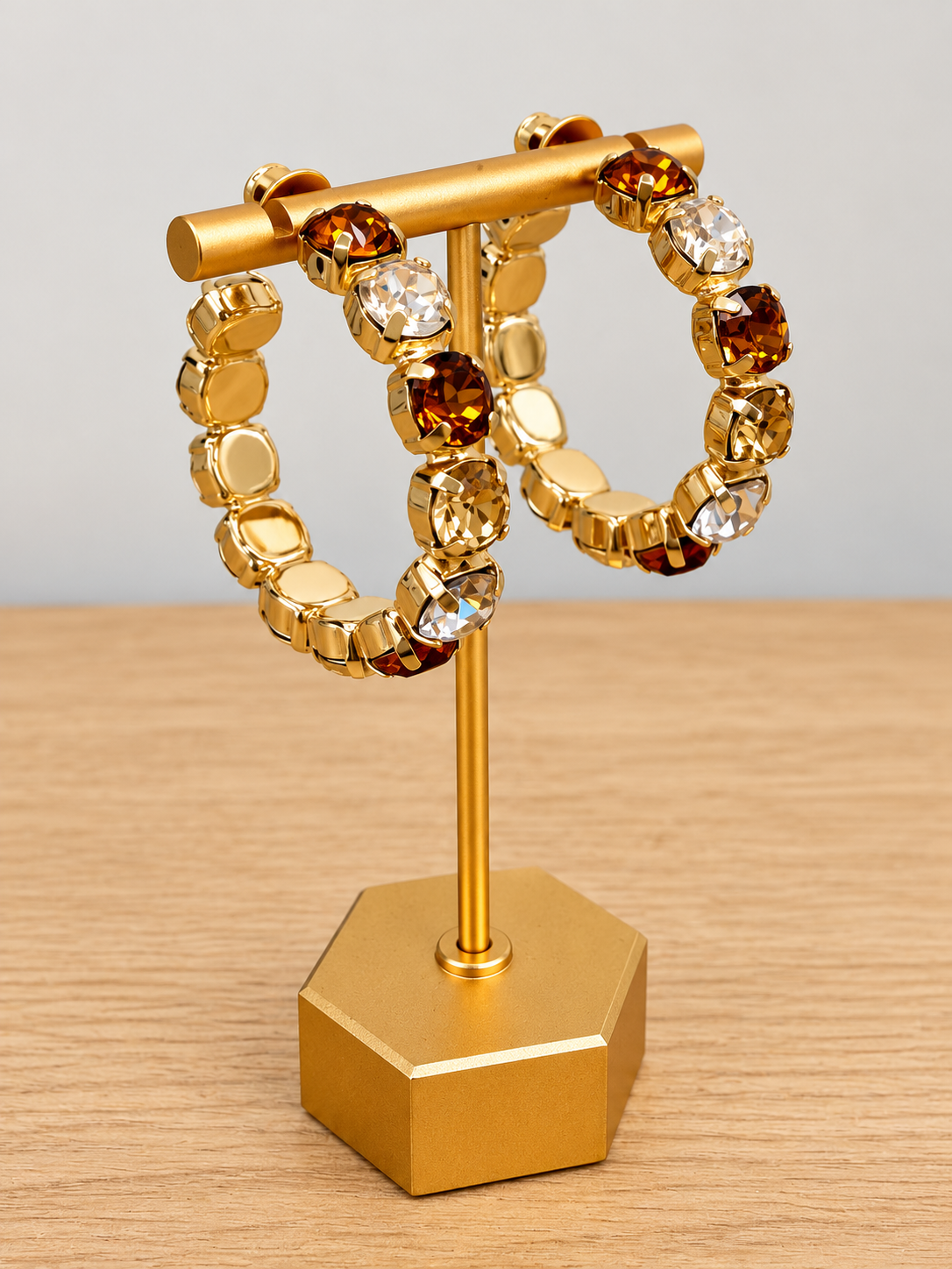 Gold-tone gemstone hoop earrings with amber and clear bead stones, side view