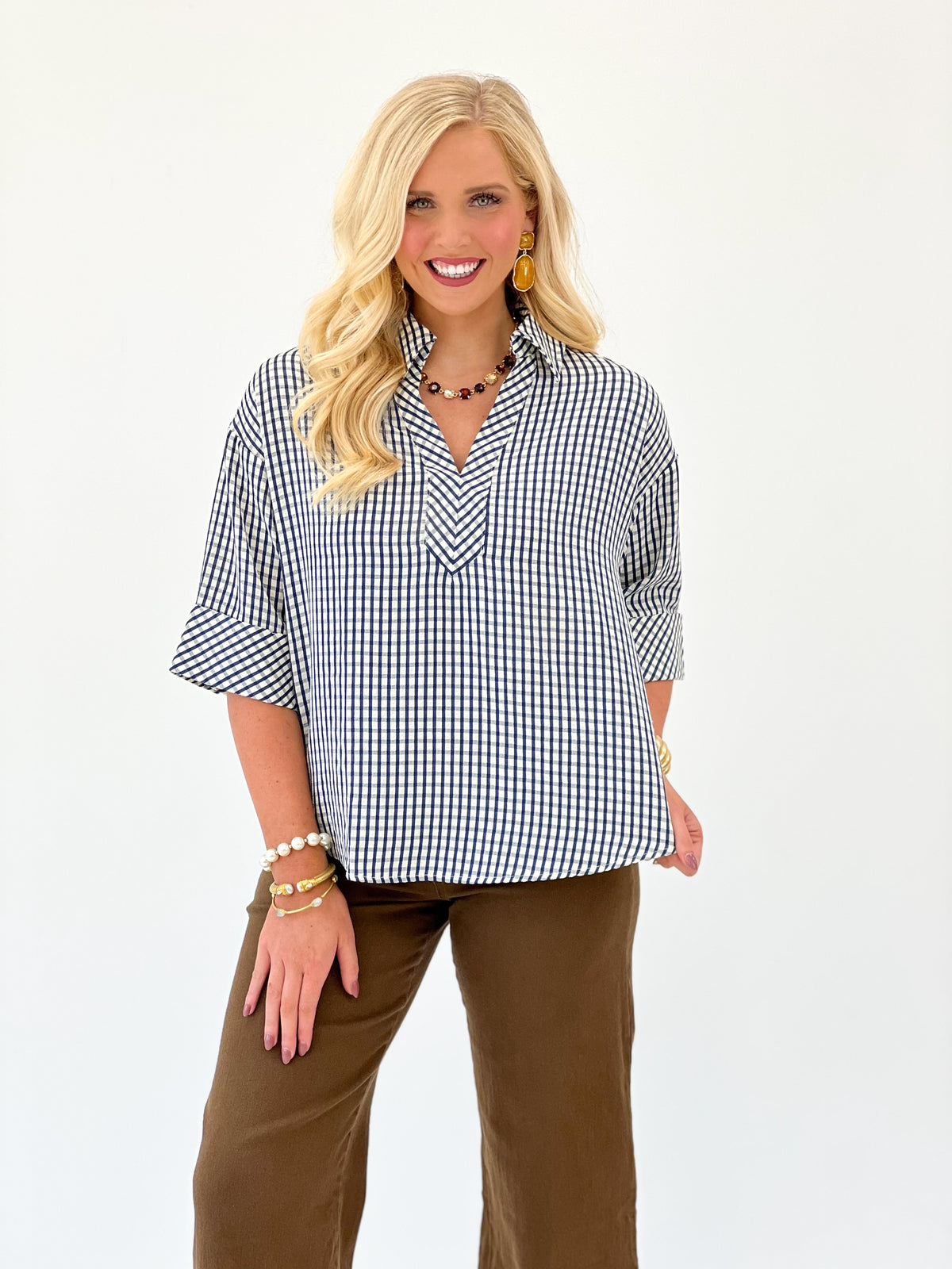 Blue and white gingham short-sleeve V-neck top, draped shoulders and loose fit.
