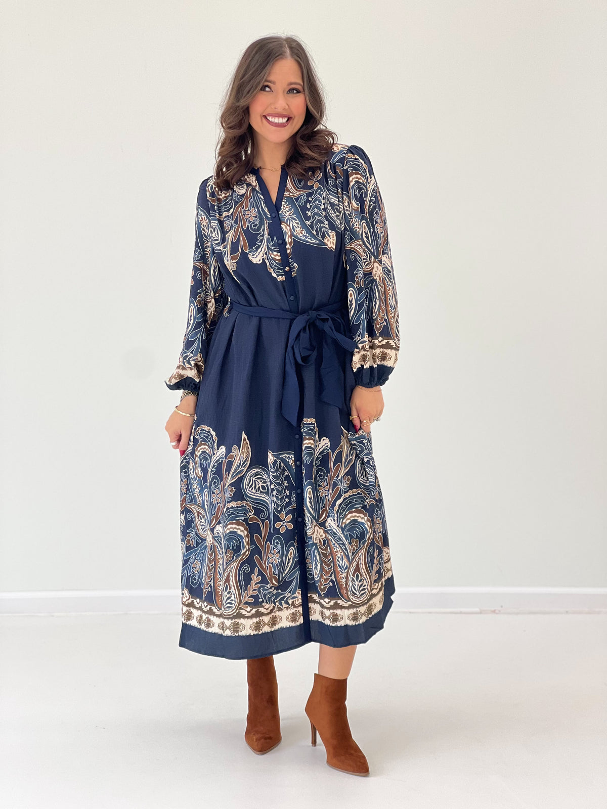Navy abstract print long-sleeve dress with buttoned V-neck, tied waist belt, border hem