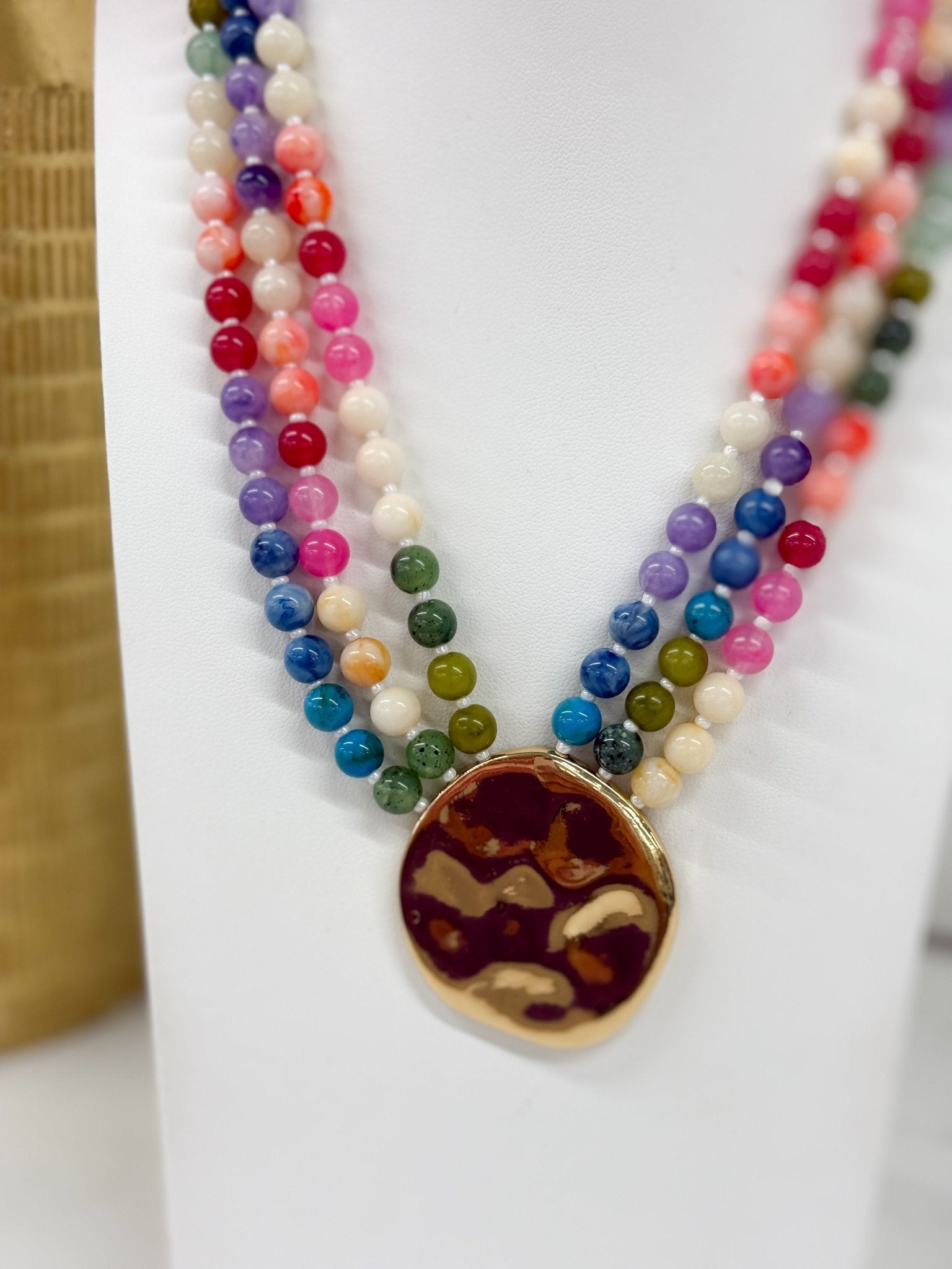 Beaded necklace layered in three strands with a charm