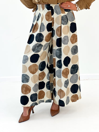 Wide-leg dot print pants, side view; cream base with navy, tan, and blue circles