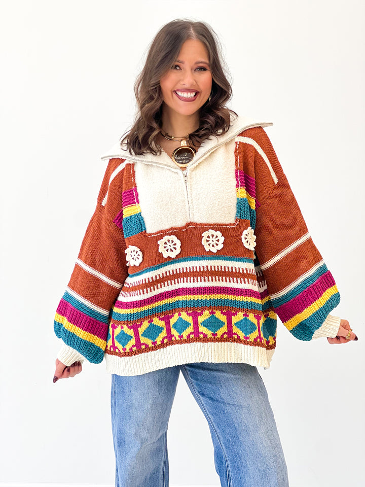 Front view of brick multi half-zip hooded sweater with colorful stripe and emblem pattern