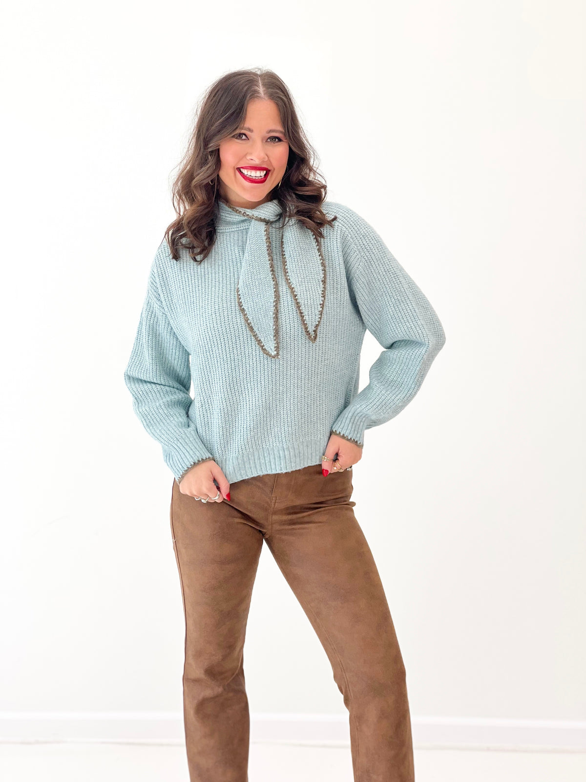 Dusty mint knit sweater with scarf-stitch neckline and draped cord tassels