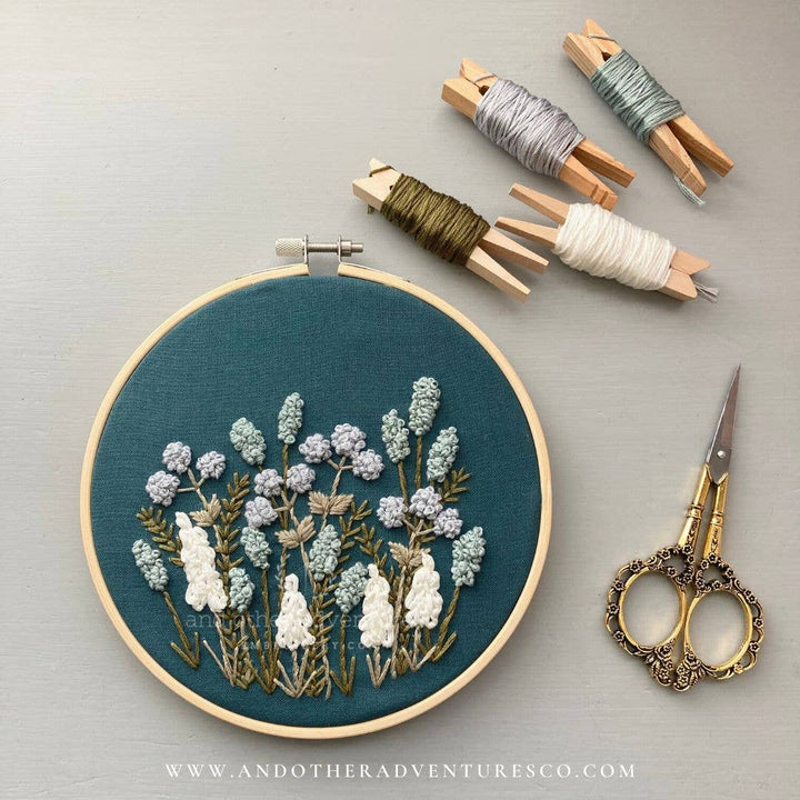 Avonlea hand embroidery kit hoop with floral embroidery on teal cloth, plus thread skeins and scissors
