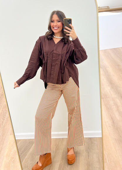 Brown V-neck pleated-waist blouse with long sleeves and gathered front panel.