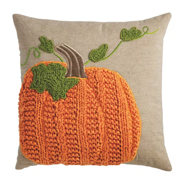 Square decorative pillow with orange knitted pumpkin and green vine embroidery on beige cover