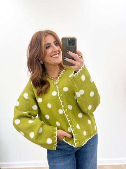 Green polka dot button-front cardigan with long sleeves and scalloped trim.